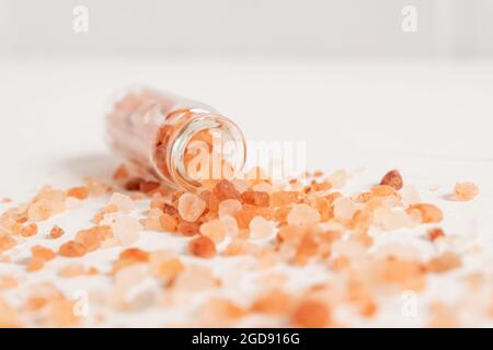 Rosa Himalaya-Salz in der kleinen Glasflasche.Nahaufnahme von rosa Kristallen aus Meersalz. Stockfoto