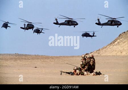 Sechs UH-60 Black Hawk-Hubschrauber der 101st Airborne Division fliegen über einer Gruppe von Soldaten in der Wüste, während ein Luftangriff während der gemeinsamen Übung Bright Star '83 stattfindet. (USAF PHOTO DF-ST-85-03755) Stockfoto