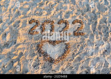 Die Nummern 2022 liegen an einem sandigen Strand mit Muschelschale. Sommer Neujahr. Ein Herz. Liebeserklärung. Urlaub, Resort und Erholung. Natur. Meer Stockfoto