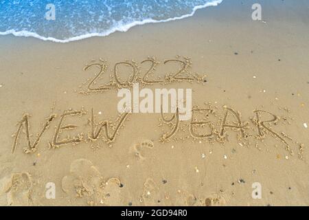 Die Zahlen 2022 stehen auf einem sandigen Strand. Wellenreiten und Surfen. Sommer Neujahr 2022. Urlaub, Resort und Erholung. Natur. Küste Stockfoto
