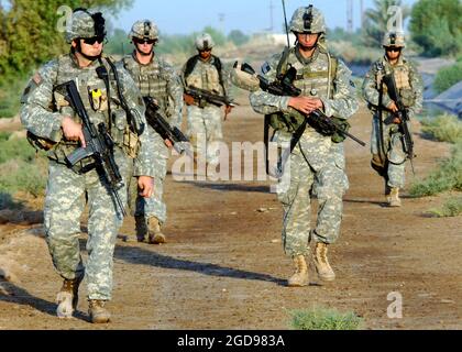 Soldaten DER US-Armee (USA), 1. Bataillon, 66. Panzerregiment (1-66. AR), 1. Brigade Combat Team (BCT), 4. Infanterie-Division (ID) führen eine lange Fußbewegung durch, um nach Waffenzwischenräumen zu suchen und ein kleines Dorf zu besuchen, um während der Operation IRAQI FREEDOM freundschaftlichen Kontakt mit seinen Bewohnern aufzunehmen. Die Soldaten sind mit KAC 5.56 mm Modular Weapon System (MWS) SOPMOD (Special Operation eigenartige Modifikation) M4s bewaffnet. (US NAVY FOTO VON MC1(AW) MICHAEL LARSON 060717-N-6901L-084) Stockfoto