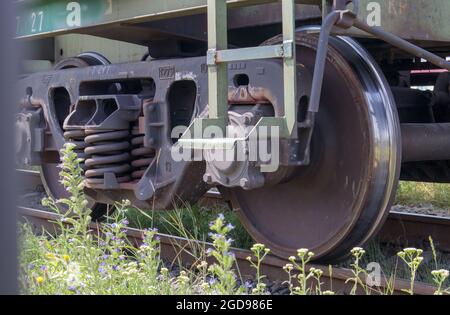 Das Fahrwerk des Schlittens mit Rädern und Federn. Personenzug, Güterzug. Industrielle Eisenbahnräder aus nächster Nähe Stockfoto