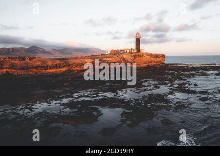 Sonnenuntergang über dem Leuchtturm von Punta Jandia (Faro de la Lola) auf vulkanischen Klippen, Fuerteventura, Kanarische Inseln, Spanien Stockfoto