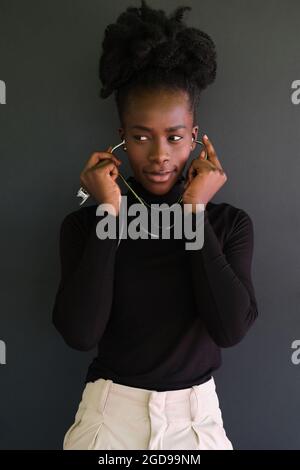 Junge weibliche afrikanische Ärztin, die das Stethoskop auf schwarzem Hintergrund verwendet. Stockfoto