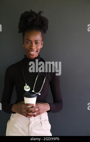 Lächelnde afrikanische Ärztin mit Stethoskop und einer Tasse Kaffee. Stockfoto