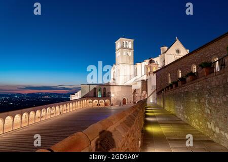 Blaue Abenddämmerung auf der Kolonnade und der beleuchteten päpstlichen Basilika des Heiligen Franziskus in Assisi, Provinz Perugia, Umbrien, Italien Stockfoto