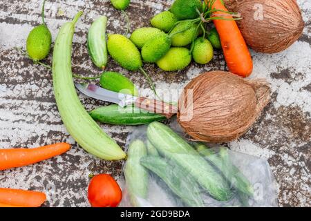 Gemüse und Obst mit einem Messer auf einem rissstrukturierten Boden verstreut Stockfoto