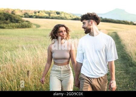Schönes heterosexuelles Paar auf einem Grasfeld, das herumläuft und küsst Stockfoto