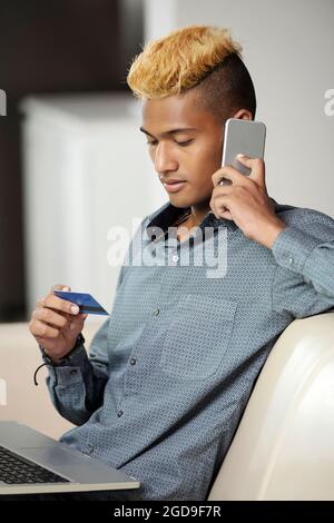 Junger Mann, der mit dem Bankmanager telefoniert, wenn er Probleme mit der neuen Kreditkarte hat Stockfoto