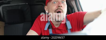 Überrascht männlichen Kurier in Uniform fährt Auto Stockfoto