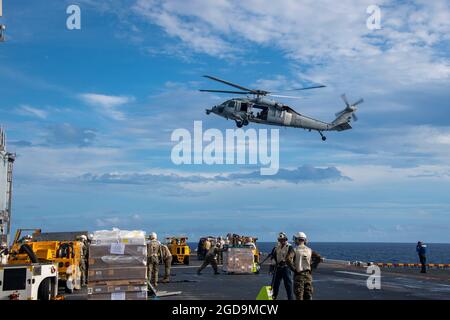 PAZIFIK (Aug 5, 2021) ein MH-60S Seahawk-Hubschrauber liefert während einer Auffüllung auf See mit dem Trockenfracht- und Munitionsschiff USNS Matthew Perry (T-AKE 9) Fracht auf dem Flugdeck des nach vorne eingesetzten amphibischen Sturmschiffes USS America (LHA 6). Amerika, das Flaggschiff der America Expeditionary Strike Group, und die 31. Marine Expeditionary Unit sind im Verantwortungsbereich der 7. Flotte der USA tätig, um die Interoperabilität mit Verbündeten und Partnern zu verbessern und als einsatzbereite Einsatztruppe für Frieden und Stabilität in der Indo-Pazifik-Region zu dienen. (USA Navy Foto von Mass Com Stockfoto