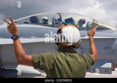 U.S. Marine Corps Lance CPL. Justin Delrio, ein Mechaniker für stationäre Flugzeuge, links, meldet Maj. Nils Alpers, F/A-18 Hornet Pilot, oben rechts, und Capt. Conner Allender, F/A-18 Hornet Aircraft Weapon Systems Officer mit Marine Fighter Attack Squadron (VMFA) 232 auf der Andersen Air Force Base, Guam, während Pacific Iron 2021, 4. August 2021. Pacific Iron 2021 konzentriert sich auf den Einsatz, den Betrieb und die Unterstützung von Kräften aus kleineren, verstreuten Stützpunkten in der Region Indo-Pazifik. (USA Marine Corps Foto von Lance CPL. Tyler Harmon) Stockfoto