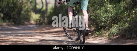 Junger Mann, der Fahrrad entlang des Pfades der Parkrückansicht reitet Stockfoto