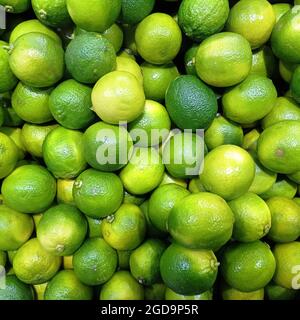 Viele saftige helle Limetten auf einer Markttheke. Nahaufnahme. Hintergrund. Stockfoto