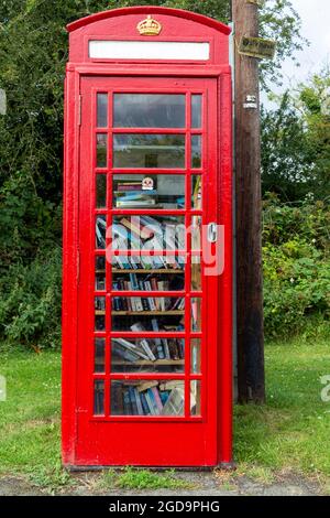 Eine rote K6-Telefondose in Großbritannien wurde außer Betrieb genommen und wird jetzt als Buchtausch verwendet Stockfoto