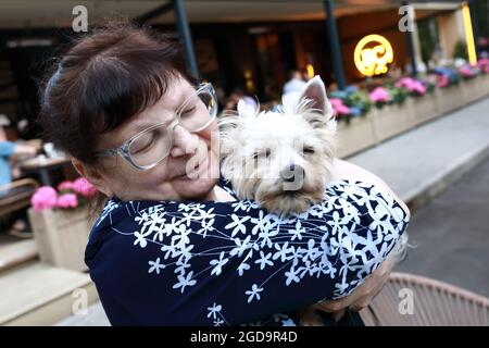 Ältere Frau hält Yorkshire Terrier Hund in den Armen im Restaurant Stockfoto