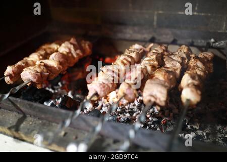 Schweinefleisch Hals Kochen auf Spieße über Holzkohle im Kamin Stockfoto