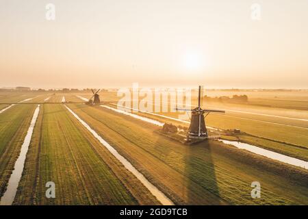Klassische holländische Windmühlen sprühen am frühen Morgen über dem Ackerland. Aarlanderveen, Niederlande. Luftaufnahme. Stockfoto