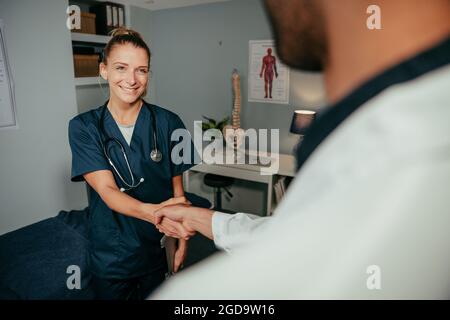 Kaukasische Krankenschwester schüttelt sich die Hände mit einem männlichen Arzt Stockfoto