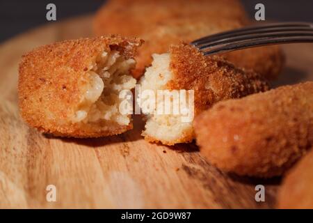 Hausgemachte traditionelle spanische Kroketten auf einem Holzbrett und schwarzem Hintergrund. Tapas. Dunkles Essen. Stockfoto