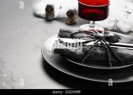 Festliche Halloween Tischdekoration mit rotem Glas, schwarzer Spinne und Horror Dekoration. Nahaufnahme. Stockfoto