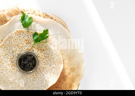 Serviert köstliche Stapel Pfannkuchen mit schwarzem Kaviar, Petersilie. Gesundes russisches Frühstück. Selektiver Fokus, Kopierbereich Stockfoto