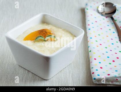 Reispudding in einer kleinen Schüssel, garniert mit Pfirsich und Minze. Stockfoto
