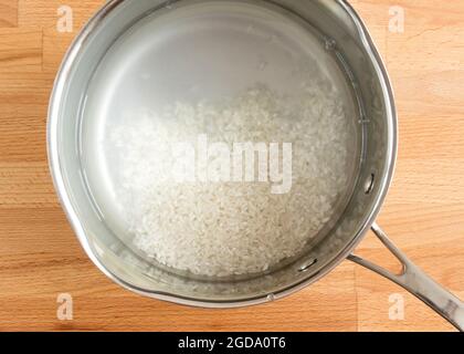 Der gewaschene Reis liegt in einer Schüssel mit Wasser. Stockfoto