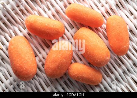 Mehrere leuchtend orange natürliche Mini-Karotten, Nahaufnahme, auf einer Weinmatte, Draufsicht. Stockfoto