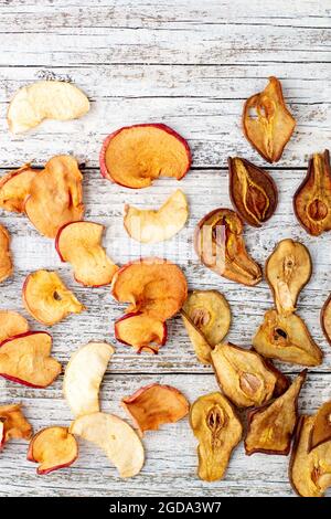 Muster eines Stapels getrockneter Birnen und Äpfel in Scheiben auf weißem Holzgrund. Getrocknete Fruchtchips. Gesunde Ernährung. Draufsicht Stockfoto