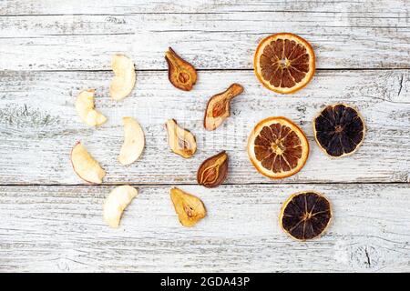 Muster eines Stapels getrockneter Birnen Zitrus und Äpfel in Scheiben auf weißem Holzhintergrund. Getrocknete Fruchtchips. Gesunde Ernährung. Draufsicht Stockfoto