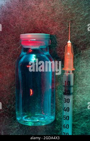 Penicillin-Fläschchen und Spritze auf einem mehrfarbigen schimmeligen Hintergrund Stockfoto