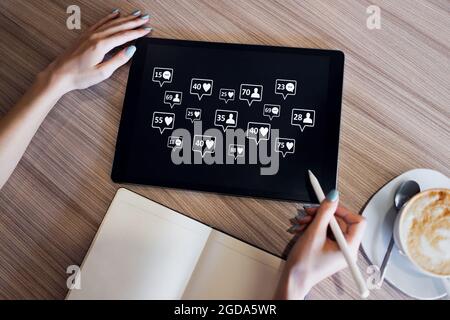 SMM, Social Media Marketing Konzept. „Gefällt mir“-Angaben, Kommentare und neue Follower-Symbole auf dem Bildschirm des Geräts. Stockfoto