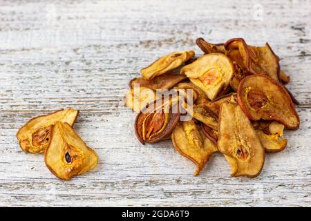 Ein Stapel getrockneter Birnen in Scheiben auf weißem Holzgrund. Getrocknete Fruchtchips. Gesunde Ernährung Stockfoto