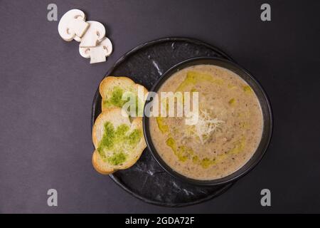 Draufsicht auf eine pürierte Pilzsuppe mit Brot auf schwarzem Hintergrund Stockfoto