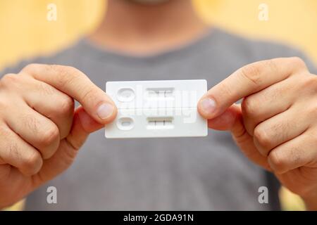 Covid 19-Schnelltest mit negativen und positiven Ergebnissen, Coronavirus-Selbsttest zu Hause, Kit mit Händen zum Nachweis von Antikörpern und Immunität. Schließen Stockfoto