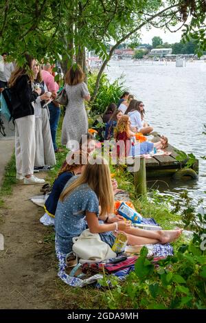 Junge Zuschauer picknicken am Treidelpfad am Ufer der Themse bei der Henley Royal Regatta 2021 Stockfoto