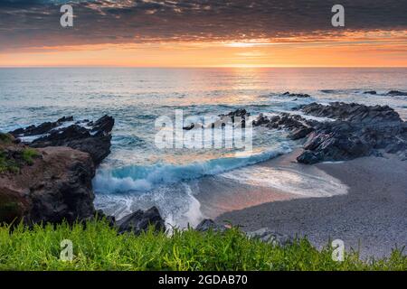 Ein wunderschöner, farbenfroher Sonnenuntergang über Little Fistral an der Küste von Newquay in Cornwall. Stockfoto