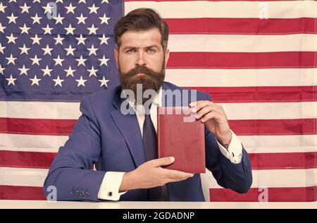 Freiheit des Druckens. Patriotischer Geschäftsmann hält Buch auf schwarzgrund amerikanischer Flagge. Amerikanische Freiheit. Unabhängigkeitstag. Juli. Stolz und Freiheit Stockfoto