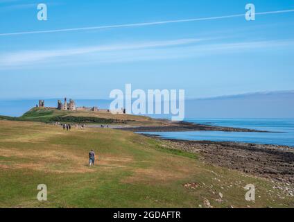 Dunstanburgh, Craster, Northumberland, Großbritannien, 23 July 2021 - Blick über den Küstenpfad zum Dunstanburgh Castle an klaren Tagen mit blauem Himmel. Stockfoto