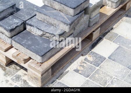 Auf einer Palette gestapelte Beton- oder gepflasterte graue Pflasterplatten oder Boden- oder Laufsteine. Betonpflaster Platten im Hinterhof oder Straßenpflaster. Backstein im Garten Stockfoto