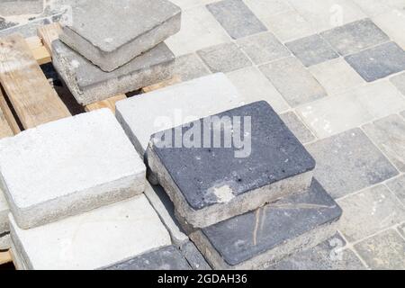 Auf einer Palette gestapelte Beton- oder gepflasterte graue Pflasterplatten oder Boden- oder Laufsteine. Betonpflaster Platten im Hinterhof oder Straßenpflaster. Backstein im Garten Stockfoto
