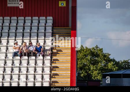 Kleine Gruppe von Fußballzuschauern, die isoliert auf Sitzen im Fußballstadion sitzen Stockfoto