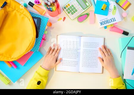 Zurück zur Schule. Obere Ansicht der modernen Schüler mit offenem Buch, Arbeitsbücher, stationär, Lehrbuch und Rucksack mit Fernunterricht an weißem Tisch bei ho Stockfoto