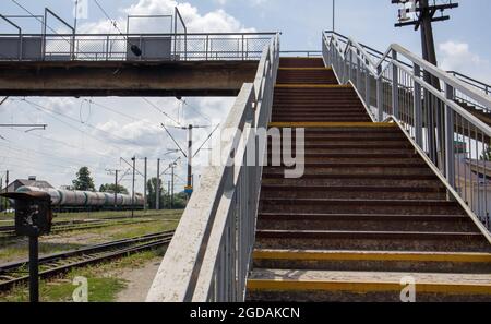 Eisenbahnbrücke mit Stufen, mit beeindruckenden Stufen in der Perspektive. Fußgängerüberweg über dem Kopf. Eine Brückentreppe verbindet eine Plattform mit einer anderen am Stockfoto