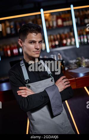 Ein hübscher Barkeeper auf der Schürze, der an der Theke stand Stockfoto