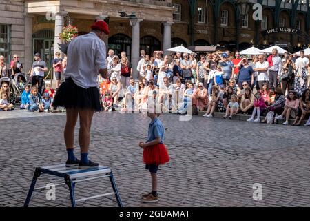 Da viele Menschen und Familien während der Schulferien in Großbritannien ihren Sommerurlaub verbringen, ist eine große Anzahl von Inlandstouristen, Wer normalerweise ins Ausland gereist ist, ist in der Hauptstadt decendiert, um die Sehenswürdigkeiten zu sehen, wie hier in Covent Garden, wo sich die Leute versammelt haben, um den Straßenkünstlern auf dem Plaza am 10. August 2021 in London, Großbritannien, zuzusehen. Nach dem Coronavirus/Covid-19-Gesundheitsproblem der letzten zwei Jahre und mit einigen Reisebeschränkungen, die noch bestehen, haben sich mehr Menschen für einen Aufenthalt entschieden, der ein Urlaub im Heimatland ist, anstatt in abro Stockfoto