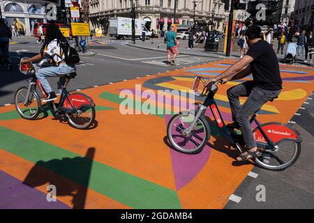 Da viele Menschen und Familien während der Schulferien in Großbritannien ihren Sommerurlaub verbringen, ist eine große Anzahl von Inlandstouristen, Wer normalerweise ins Ausland gereist ist, hat sich in der Hauptstadt decendiert, um die Sehenswürdigkeiten zu sehen, wie man hier im Piccadilly Circus sieht, als die Menschen am 10. August 2021 in London, Großbritannien, die neuen grafischen und gemusterten mehrfarbigen Fußgängerübergänge überqueren. Nach dem Coronavirus/Covid-19-Gesundheitssorge der letzten zwei Jahre und mit einigen Reisebeschränkungen, die noch bestehen, haben sich mehr Menschen für einen Aufenthalt entschieden, der ein Urlaub in ihrem Heimatland ist Stockfoto