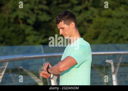 Analyse seines Ergebnisses. Der Mann überprüft die Zeit nach dem Training auf der Uhr. Belastungsdauer. Sportliches Timing Stockfoto