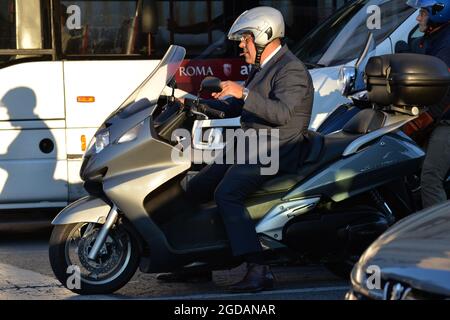 Italienischer Herr auf silbernem Motorrad, der eine Zigarre raucht, die im Verkehr feststeckt Stockfoto